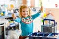 Cute little toddler girl helping in the kitchen with dish washing machine. Happy healthy blonde child sorting knives Royalty Free Stock Photo