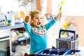 Cute little toddler girl helping in the kitchen with dish washing machine. Happy healthy blonde child sorting knives Royalty Free Stock Photo