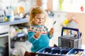 Cute little toddler girl helping in the kitchen with dish washing machine. Happy healthy blonde child sorting knives Royalty Free Stock Photo