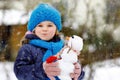 Cute little toddler girl making mini snowman and eating carrot nose. Adorable healthy happy child playing and having fun