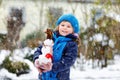 Cute little toddler girl making mini snowman and eating carrot nose. Adorable healthy happy child playing and having fun