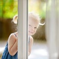 Cute little toddler girl peeking into a window Royalty Free Stock Photo