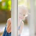 Cute little toddler girl peeking into a window Royalty Free Stock Photo