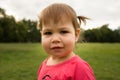 Cute Little toddler girl in pink dress playing in park in front of green grass Royalty Free Stock Photo