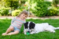 Cute little toddler girl playing with family dog in garden. Happy smiling child having fun with dog, hugging playing Royalty Free Stock Photo