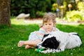 Cute little toddler girl playing with family dog in garden. Happy smiling child having fun with dog, hugging playing Royalty Free Stock Photo