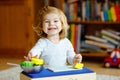 Cute little toddler girl playing at home with eco wooden toys. Happy healthy excited child cutting vegetables and fruits Royalty Free Stock Photo