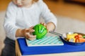 Cute little toddler girl playing at home with eco wooden toys. Happy healthy excited child cutting vegetables and fruits Royalty Free Stock Photo