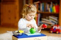 Cute little toddler girl playing at home with eco wooden toys. Happy healthy excited child cutting vegetables and fruits Royalty Free Stock Photo