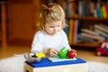 Cute little toddler girl playing at home with eco wooden toys. Happy healthy excited child cutting vegetables and fruits Royalty Free Stock Photo