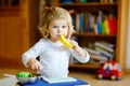 Cute little toddler girl playing at home with eco wooden toys. Happy healthy excited child cutting vegetables and fruits Royalty Free Stock Photo