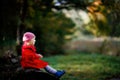 Cute little toddler girl in red coat making a walk through autumn forest. Happy healthy baby enjoying walking with Royalty Free Stock Photo