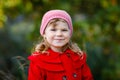 Cute little toddler girl in red coat making a walk through autumn forest. Happy healthy baby enjoying walking with Royalty Free Stock Photo