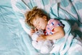 Cute little toddler girl sleeping in bed with favourite soft plush toy dog. Adorable baby child dreaming, healthy sleep Royalty Free Stock Photo