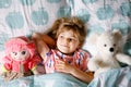 Cute little toddler girl sleeping in bed with favourite soft plush toy doll and teddy bear. Adorable baby child dreaming Royalty Free Stock Photo