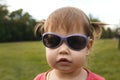 Cute Little toddler girl in sunglasses in park in front of green grass Royalty Free Stock Photo