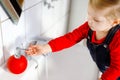 Cute little toddler girl washing hands with soap and water in bathroom. Adorable child learning cleaning body parts