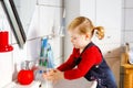 Cute little toddler girl washing hands with soap and water in bathroom. Adorable child learning cleaning body parts