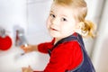 Cute little toddler girl washing hands with soap and water in bathroom. Adorable child learning cleaning body parts