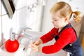 Cute little toddler girl washing hands with soap and water in bathroom. Adorable child learning cleaning body parts