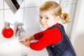 Cute little toddler girl washing hands with soap and water in bathroom. Adorable child learning cleaning body parts