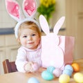 Cute little toddler girl wearing Easter bunny ears playing with colored pastel eggs. Happy baby child unpacking gifts Royalty Free Stock Photo