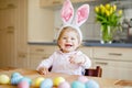 Cute little toddler girl wearing Easter bunny ears playing with colored pastel eggs. Happy baby child unpacking gifts Royalty Free Stock Photo