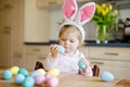 Cute little toddler girl wearing Easter bunny ears playing with colored pastel eggs. Happy baby child unpacking gifts Royalty Free Stock Photo