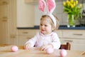 Cute little toddler girl wearing Easter bunny ears playing with colored pastel eggs. Happy baby child unpacking gifts Royalty Free Stock Photo