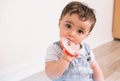 Cute little toddler wearing denim dungaree and chewing on a colorful teether ring