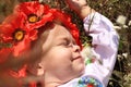 A cute little Ukrainian Caucasian girl in a wreath and an embroidered shirt is resting lying on the grass Royalty Free Stock Photo