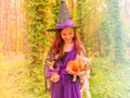 Cute little witch with a pumpkin. Beautiful young child girl in witch costume outdoors. Halloween Royalty Free Stock Photo