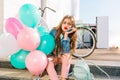 Cute long-haired girl with face expression of discontent waiting for friends who are late, holding helium balloons Royalty Free Stock Photo