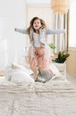 Cute long-haired girl jumping high on the bed and smiling happily Royalty Free Stock Photo