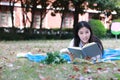 Cute lovely Asian Chinese pretty girl wear student suit in school lying on grass lawn reading book enjoy causian time Royalty Free Stock Photo