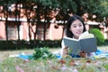 Cute lovely Asian Chinese pretty girl wear student suit in school lying on grass lawn reading book enjoy causian time Royalty Free Stock Photo