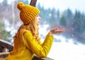 Cute lovely girl in a knitted cap and sweater holding out palm of the hand under falling snow outside the city Royalty Free Stock Photo