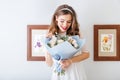 Cute lovely happy young woman looking at bouquet of flowers