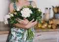 Cute and lovely peony flowers in women`s hands.. many layered petals. Bunch pale white peonies flowers light gray background