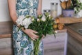 Cute and lovely peony flowers in women`s hands.. many layered petals. Bunch pale white peonies flowers light gray background