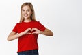 Cute and lovely smiling little girl, showing heart sign and looking tenderly at camera, concept of family and care