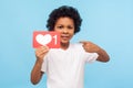 Cute lovely young boy with curly hair pointing to heart Like symbol, icon to appreciate content Royalty Free Stock Photo