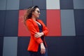 Cute lovely young woman in sunglasses, red jacket, fashion hat, standing over abstract background outdoor. Portrait fashion model Royalty Free Stock Photo