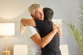 Cute loving caring old elderly senior father embracing hugging his adult caucasian son while standing together at home in living