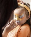 Cute makeup little tiger. girl getting face painting outdoors,