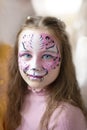 Cute makeup little tiger. girl getting face painting outdoors,