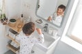 Cute male kid in pajamas cleaning teeth with eco friendly toothbrush comfortable minimalist bathroom