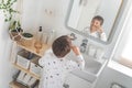 Cute male kid in pajamas cleaning teeth with eco friendly toothbrush comfortable minimalist bathroom