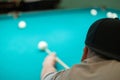 Cute man aiming a cue at a billiard ball. In the evening, a man relaxes and relaxes while playing billiards. A man hits