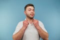 Cute man with bristles in a white T-shirt posing at camera with a smile on his face on a blue background Royalty Free Stock Photo